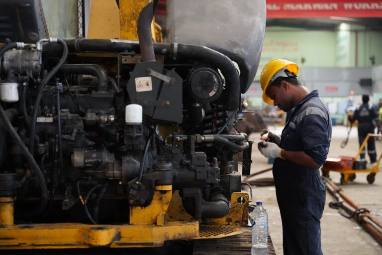 A field service engineer performing on-site maintenance using diagnostic tools on industrial equipment.